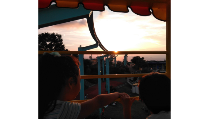 ぷかぷかパンダの乗り物から夕日と大阪平野を眺める子どもたち