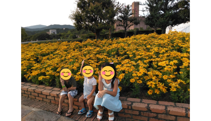 黄色いお花の前に座る子どもたち